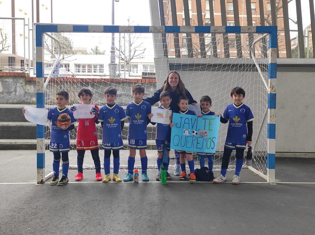 Equipo de fútbol infantil posando en la portería con una pancarta de apoyo a Javi