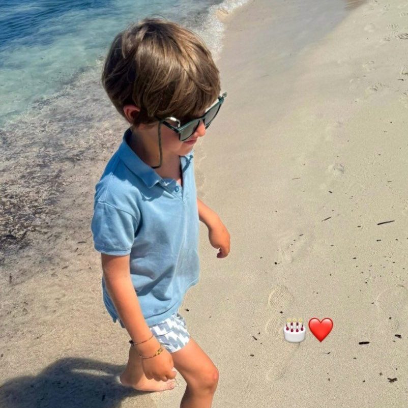 Javi caminando por la orilla de la playa con gafas de sol y polo azul
